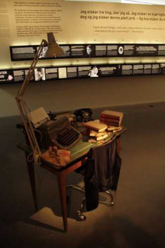 Et skrivebord fylt med bøker og en skrivemaskin
