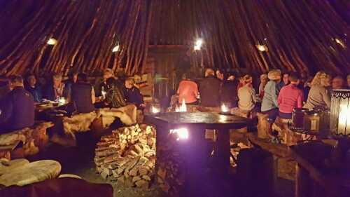 People around tables inside the hut, enjoying thenmselves