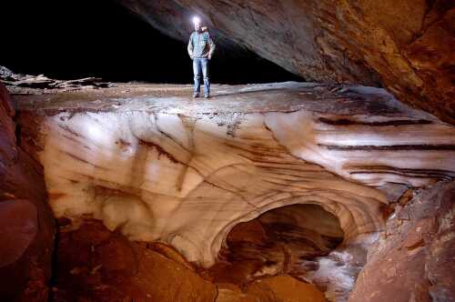 En mann står på is inne i en grotte