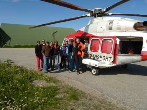 Group of people standing outside an helicopter